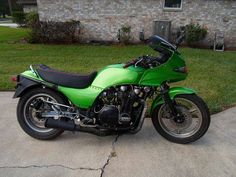 a green motorcycle parked in front of a house