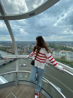 a woman standing on top of a glass observation tower looking down at the city below