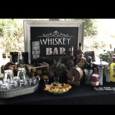 a table topped with bottles and glasses next to a sign that says whiskey bar on it