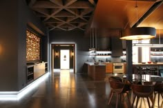 an open kitchen and dining room area with lights on the ceiling, lighting up the walls