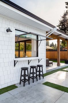 three stools are sitting in front of a white brick bar with black barstools