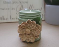 a green mason jar with burlap flowers on it