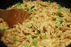 a wooden spoon is in a pasta dish with broccoli