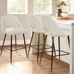 three white bar stools sitting on top of a kitchen counter next to a window