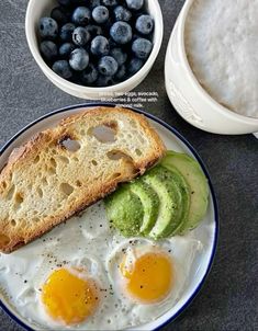 an egg, avocado and toast on a plate next to some blueberries