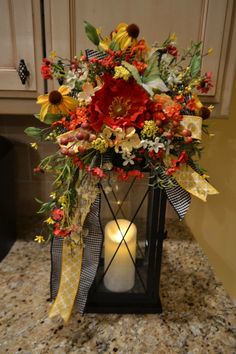 a vase with flowers and a candle on a counter