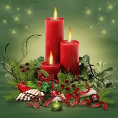 two red candles sitting on top of a table next to holly wreaths and candy