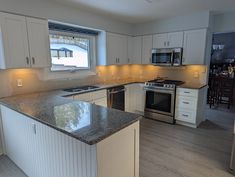 a kitchen with white cabinets and granite counter tops