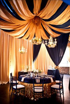 a chef standing in front of a table with black and gold drapes on it