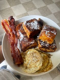 a breakfast plate with bacon, eggs and french toast