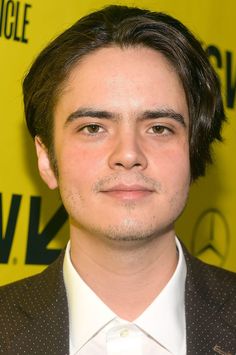 a close up of a person wearing a suit and tie with a yellow wall in the background