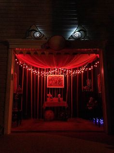 an open doorway with red lights and curtains on the outside, in front of a brick building