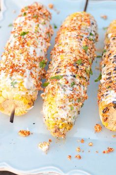 three corn on the cob covered in cheese and seasoning