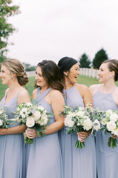 a group of women standing next to each other holding bouquets in their hands and laughing