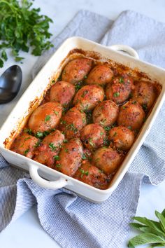 a casserole dish filled with meatballs and garnished with parsley