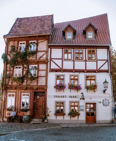 an old building with many windows and flowers on the outside, next to a cobblestone street