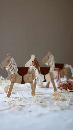 three wooden toy horses on a table with string sprinkles and confetti