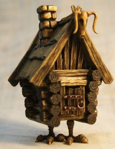 a small wooden house with a cat on the roof and an eyeball in its mouth