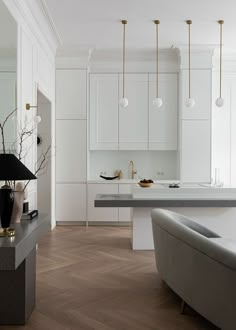 a modern kitchen with white cabinets and marble counter tops, gold accents on the pendant lights