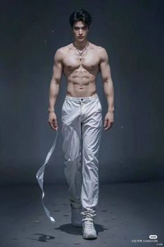 a shirtless man is walking down the runway wearing white pants and no shirt on