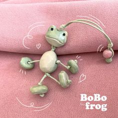 a frog figurine sitting on top of a pink blanket with the word bobo frog written across it