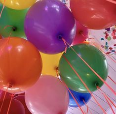 many balloons are in the air with some string attached to them and one is purple, green, red, yellow and orange