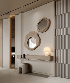 two circular mirrors on the wall above a table and stool in a room with white walls