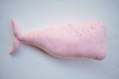 a pink stuffed whale laying on top of a white table