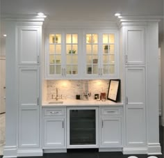 a kitchen with white cabinets and marble counter tops