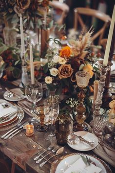 the table is set with candles, plates and silverware for an elegant dinner party