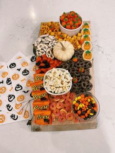 an assortment of halloween snacks on a table with pumpkins, candy and candies