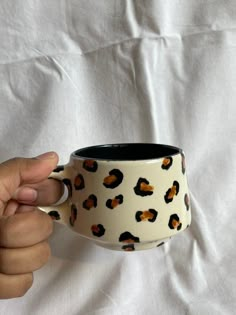 a hand holding a black and white coffee cup with leopard print on it's side