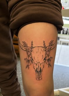 a woman with a tattoo on her thigh has a cow skull and flowers around it