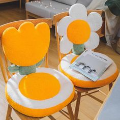 two chairs with flower cushions on them and a book in the middle one has a green ribbon