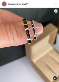 a woman's hand with three different rings on her finger and one is holding the other