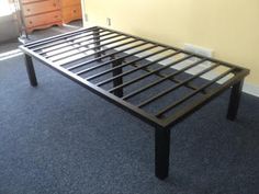 a metal bed frame sitting on top of a blue carpeted floor next to a dresser