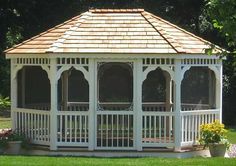 a white gazebo sitting on top of a lush green field