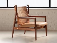 a wooden chair sitting in front of a window next to a brick wall and floor