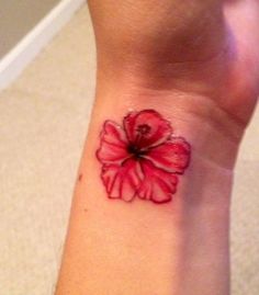 a red flower on the wrist is shown in this image, it appears to be a tattoo