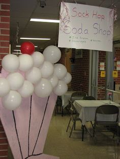 balloons are in the shape of an umbrella with a sign hanging from it that says sock hop edda shop