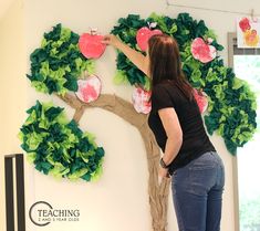 a woman standing in front of a tree made out of paper