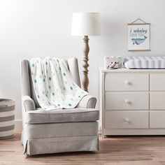 a chair with a blanket on it next to a dresser