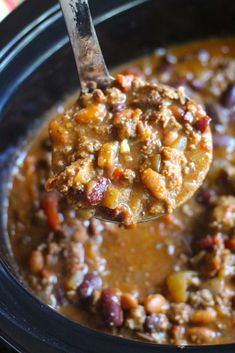 a spoon full of chili and beans in a crock pot