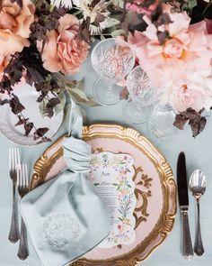 the table is set with pink flowers and silverware, along with an antique china plate