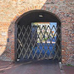 an open gate on the side of a brick building with a stop sign in the background