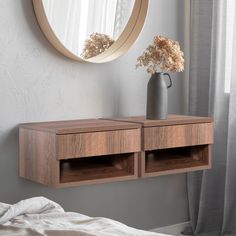 two wooden drawers sit in front of a round mirror on the wall next to a bed