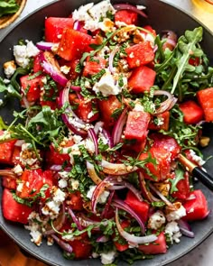 watermelon salad with feta cheese and onions in a black bowl on a table