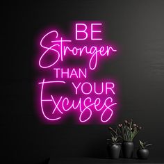 a pink neon sign that says be stronger than your excess on a black wall