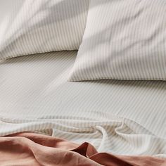 an unmade bed with white and pink sheets