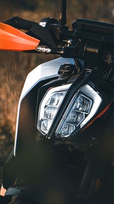 the front light of a motorcycle parked in a grassy area with tall grass behind it